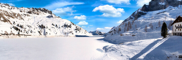 Passo Fedaia. View of frozen Fedaia lake from the dam. Passo Fedaia is a mountain pass traversed by...