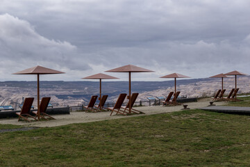 empty deck chairs with umbrellas made of metal in front of open pit mining of hambach terra nova in...