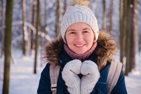 Happy Asian woman walking in winter snow forest. Cold weather hat and warm coat. idea and concept of healthy active lifestyle and good mood in any weather