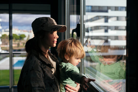 Soldier woman with son looking out window