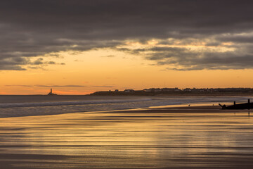 Fototapeta na wymiar Sunrise to start the day at Blyth beach in Northumberland, with St Mary's Lighthouse in the distance