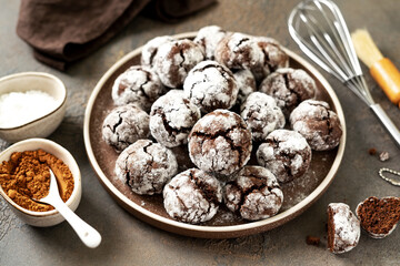 Homemade chocolate and coffee crinkle cookies in a white plate on the kitchen table. Traditional American cookies for Christmas with cracks and powdered sugar on a culinary background