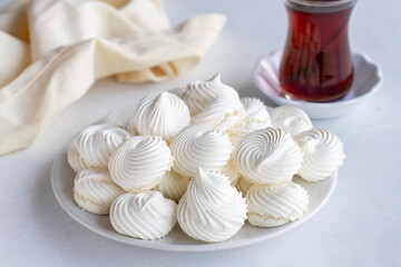 Small white meringues in a white dish. Macro shot. Horizontal view