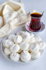 Small white meringues in a white dish. Macro shot. Vertical view