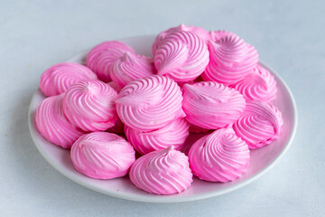 Small pink meringues in a white dish. Macro shot. Horizontal view