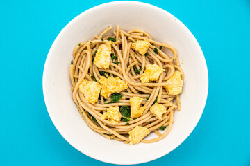 Top view of pasta with chicken and spinach on cyan background