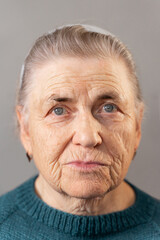 The face of an elderly woman of the 80s with deep wrinkles. Looks at the camera. Portrait of an old...