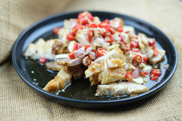 Crispy pork salad lime garlic and red paprika on a black dish (Moo Ma nao).