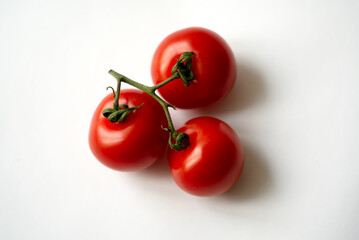 Three red tomatoes with panicle against white background. Photo taken December 30th, 2021, Zurich, Switzerland.