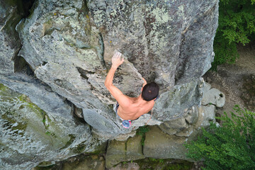 Strong male climber climbing steep wall of rocky mountain. Sportsman overcoming difficult route. Engaging in extreme sports hobby concept