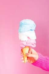 Girl wearing pink sweater and holding a cotton candy ice cream. Light pink background.