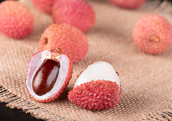 Half a lychee and several whole lychees on burlap