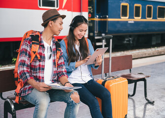 Man and woman traveler tourist use headphone with tablet at train station