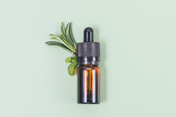 Essential oil bottle with dropper next to fresh herbs