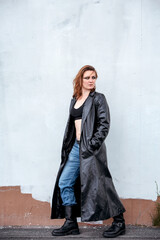 brunette woman in jeans and black leather coat standing on the street