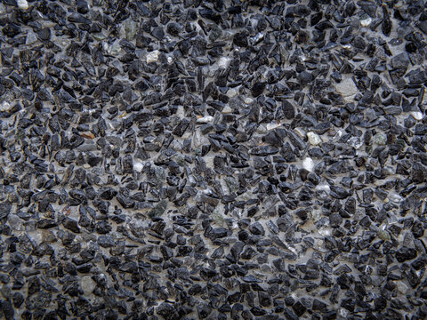 Gray small stones ground texture and background, dark color of crushed granite gravel, close up.