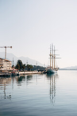 White sailboat and boats are moored at the pier of the town of Tivat