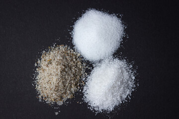 Different types of salt on a black background. Fine salt and salt with spices.