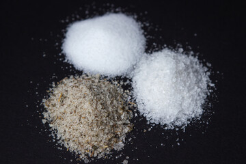 Different types of salt on a black background. Fine salt and salt with spices.