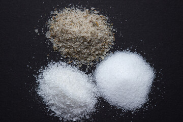 Obraz na płótnie Canvas Different types of salt on a black background. Fine salt and salt with spices.