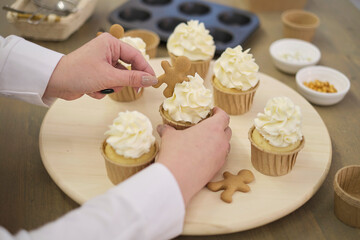 Women in pastry bakery as confectioner glazing muffins with icing bag, close-up