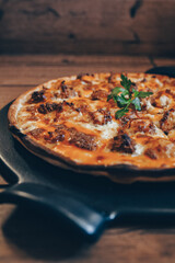 Buffalo chicken pizza pie on pizza stone with wooden background