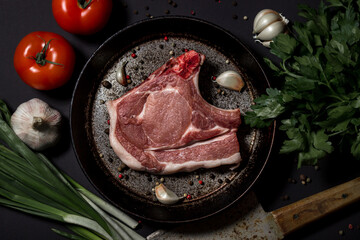 Pork meat on a black background. Raw meat loin with bone in a skillet. Meat cooking