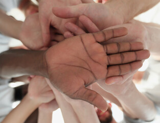smiling young people making a tall tower out of their hands