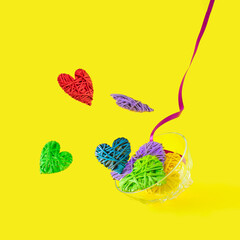 Colorful hearts on a yellow background along with a purple decorative ribbon. minimal romantic concept. Creative love idea.