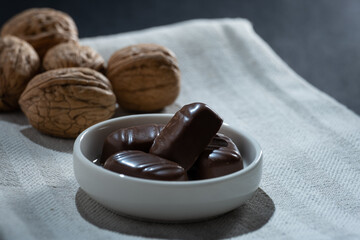 Closeup of a pile of walnut-filled chocolate confections on a small plate.