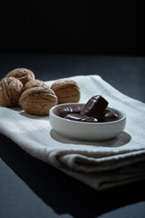 Closeup of a pile of walnut-filled chocolate confections on a small plate.