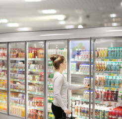 Woman choosing frozen food from a supermarket freezer.