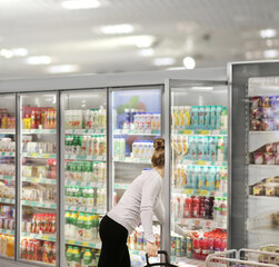 Woman choosing frozen food from a supermarket freezer.