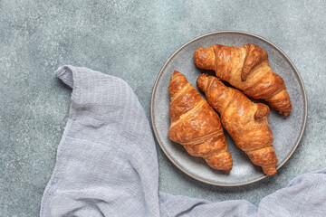 Fresh croissants close-up in a plate on gray grunge background Top view, flat lay.