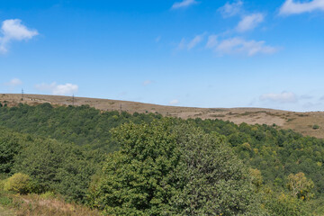 Fototapeta premium Mountain landscape with green forest and blue sky.