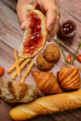 Breads. Buns with jam. Hand holding slice of bread with jam and other buns blurred in the background.