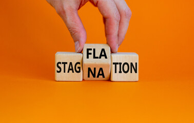 Stagflation or stagnation symbol. Businessman turns cubes, changes the word stagnation to stagflation. Beautiful orange background, copy space. Business, stagflation or stagnation concept.