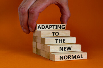 Adapting to the new normal symbol. Wooden blocks with words Adapting to the new normal on orange...