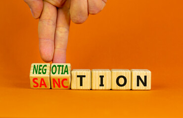 Sanction or negotiation symbol. Businessman turns cubes, changes the word sanction to negotiation. Beautiful orange table, orange background, copy space. Business, sanction or negotiation concept.