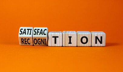 Satisfaction and recognition symbol. Turned wooden cubes and changed the word recognition to satisfaction. Beautiful orange background, copy space. Businesss satisfaction and recognition concept.