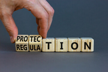 Protection and regulation symbol. Businessman turns cubes changes the word regulation to protection. Beautiful grey table, grey background, copy space. Business, protection and regulation concept.