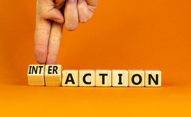 Action or interaction symbol. Businessman turns wooden cubes and changes the word action to interaction. Beautiful orange background, copy space. Business and action or interaction concept.