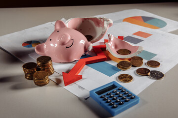 Financial crisis and bankruptcy concept. A broken piggy with stuck of coins, calculator and arrow...