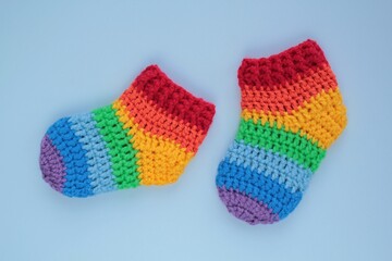 Rainbow crochet knitted booties socks on blue background. Baby shower party decoration. First birthday, newborn gift