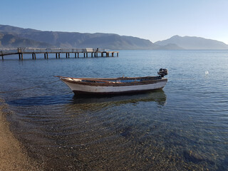 empty wooden fishing boat moored to the seashore. against the background of the mountains. boat at...
