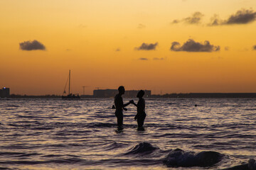 Dos amigos salud&aacute;ndose afectivamente durante el atardecer en playa norte en Isla Mujeres, 