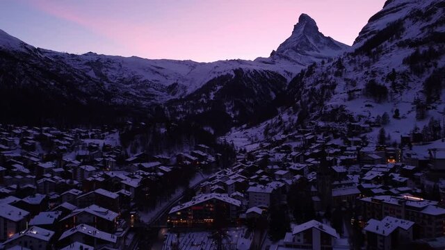 Aerial drone footage of the sunset over the famous Zermatt village with the Matterhorn peak in winter in the alps in Switzerland. 