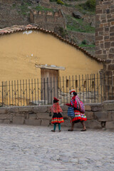 Woman walking dressed in traditional Andean clothing in the town of Olaytaytambo, Peru