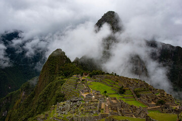 views of Macchu Picchu through the mist with clouds, Peru