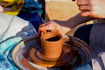 Close-up view of man working on a potter's wheel and making a clay pot outdoors, selective focus.
Pots, dishes and other baked clay products.